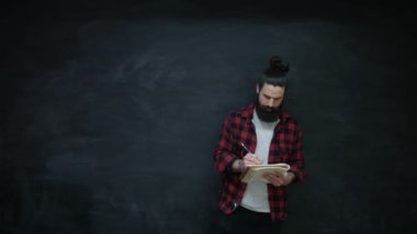 4 k düşünen hipster adam not defterinde kara tahta zemin üzerine yazma
