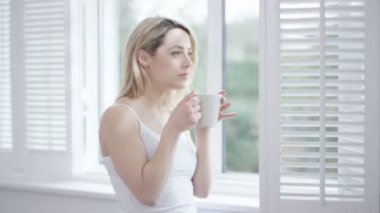 4k evde kahve zevk ve pencereden dışarı bakıyor kadın