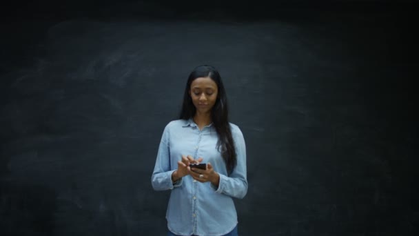 Gülen Kadın Smartphone Kullanarak Iki Yanda Yukarıda Kara Tahta Arıyor — Stok video