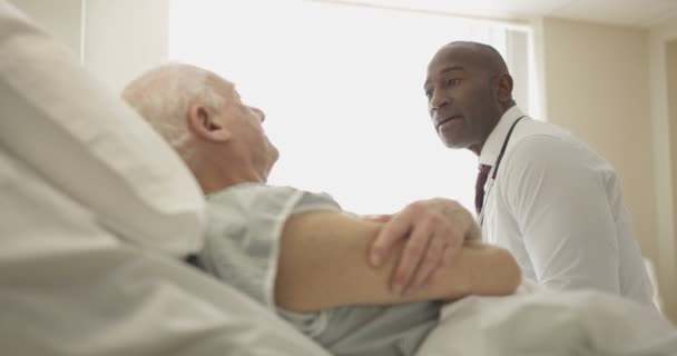 Дружелюбный Доктор Утешает Пожилого Пациента Кровати — стоковое видео
