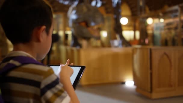恐竜に夢中になって探している博物館 タブレットを持った少年 — ストック動画