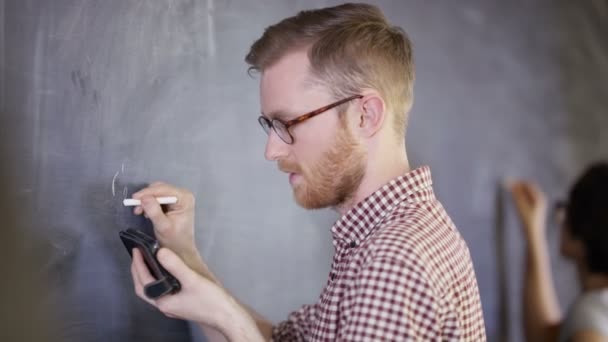 学生看智能手机 在黑板上写数学方程式 — 图库视频影像