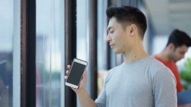 4 k Asya iş adamı pencere yanında duran ve şehir ofis cep telefonuyla konuşuyor