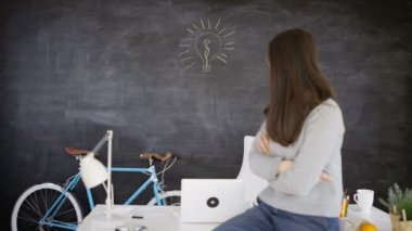 4k ampul arkasında yazı tahtası çizilmiş ile masaya oturan kadın