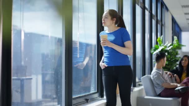 カジュアルな実業家コーヒーを飲むと オフィスの窓から景色を眺めて — ストック動画