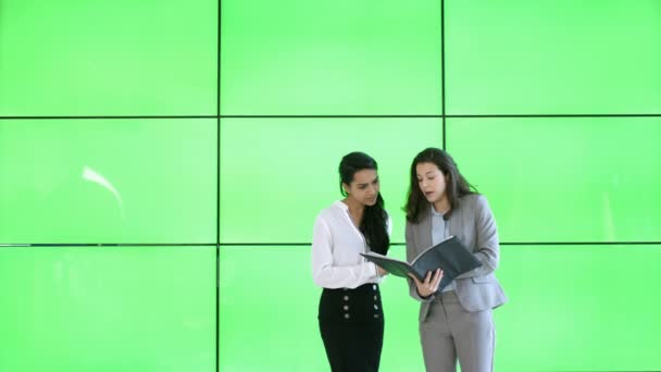 Geschäftsfrauen Diskutieren Papierkram Ordner Vor Grünem Hintergrund — Stockvideo