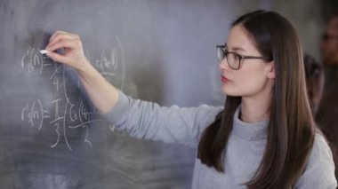 4 k genç akıllı kadın yazı tahtası üzerinde matematiksel Denklem yazma