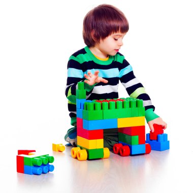 Beyaz arka plan üzerinde Lego oynarken küçük tatlı çocuk