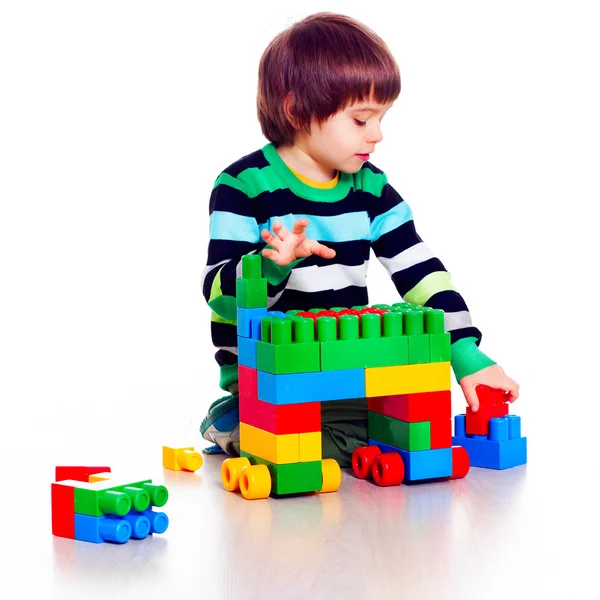 Маленький симпатичный мальчик играет Лего на белом фоне — стоковое фото