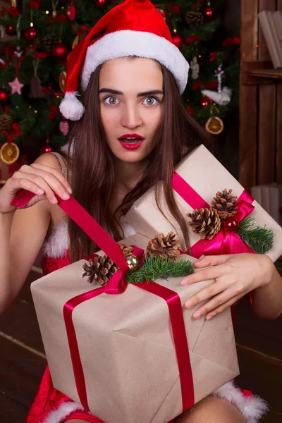 Sorpresa Santa ragazza in cappelli di Babbo Natale apertura confezione regalo vicino a Natale — Foto Stock