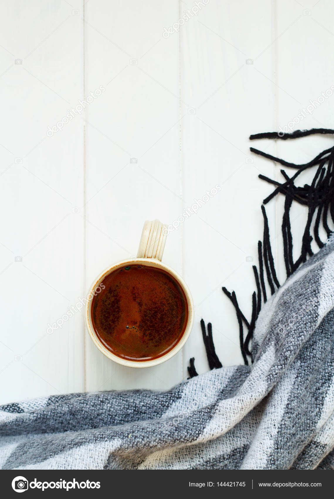 Taza de café negro, a cuadros de punto blanco, sobre fondo