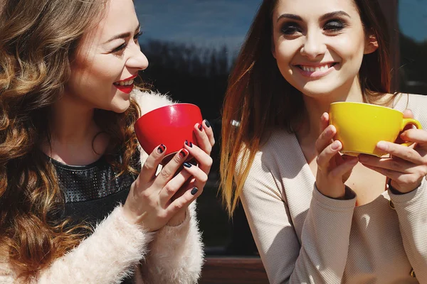 Two young pretty woman laughing outdoors and drinking coffee. Li — Stock Photo, Image