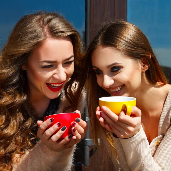 Two young pretty woman laughing outdoors and drinking coffee. Li — Stock Photo, Image