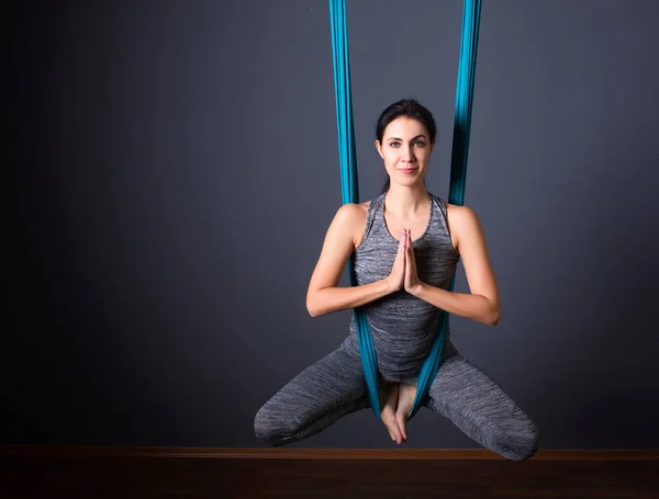 Ung vacker brunett kvinna gör flyga yoga. Sitter i hängmattan — Stockfoto