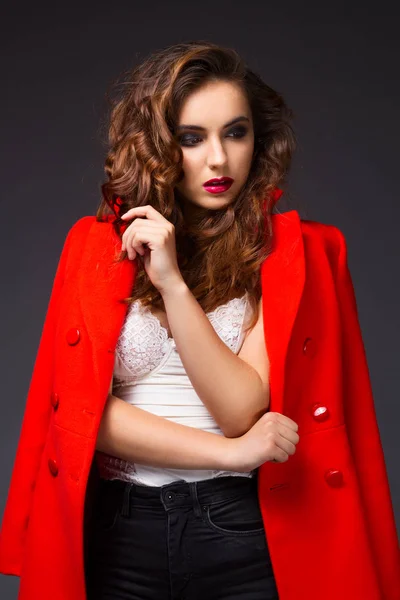 Retrato de una hermosa joven con abrigo rojo y jeans negros — Foto de Stock