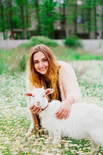 Giovane bella donna nel campo con bella capretta bianca — Foto Stock