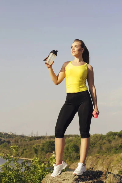 Joven hermosa mujer haciendo ejercicios deportivos y beber agua al aire libre — Foto de Stock