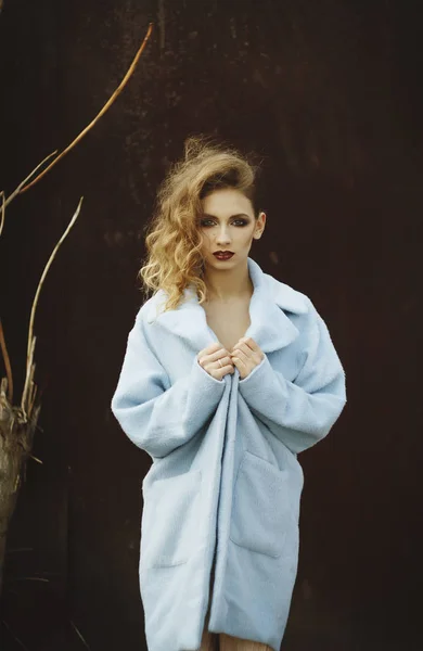 Young beautiful blonde woman posing in blue coat outdoors — Stock Photo, Image