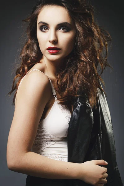Güzel genç kadın deri ceketle üzerinde gri backgro poz