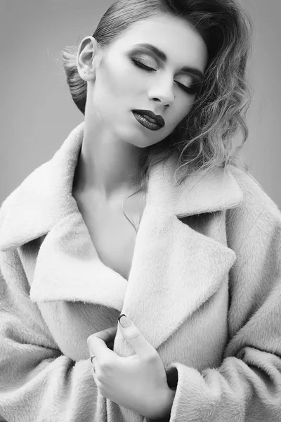 Mladá krásná blondýnka pózuje v kabátě venku — Stock fotografie
