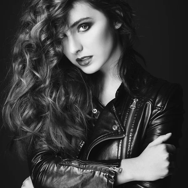 Krásná mladá žena pózuje v černé kožené bundě nad šedá b — Stock fotografie