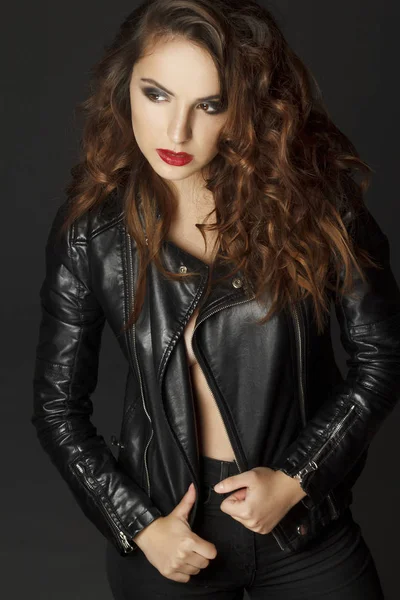 Siyah deri ceket gri b üzerinde poz güzel genç kadın