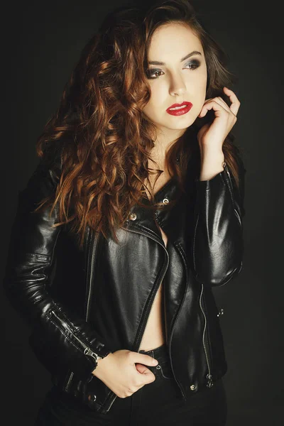 Beautiful young woman posing in black leather jacket over grey b — Stock Photo, Image