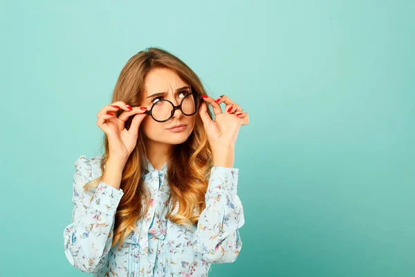 Chica bastante reflexiva con gafas sobre fondo azul —  Fotos de Stock