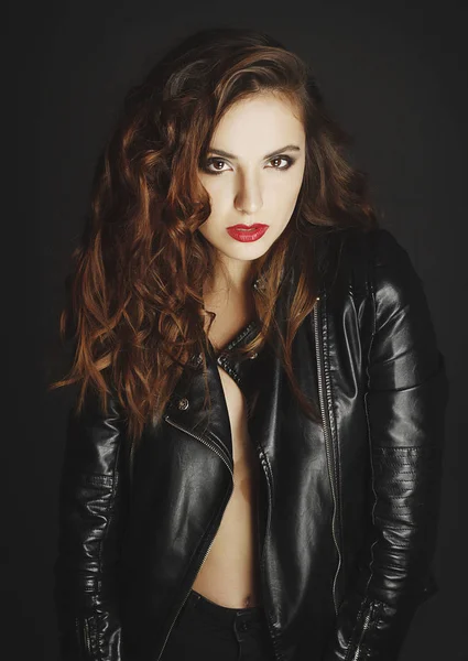 Beautiful young woman posing in black leather jacket over grey b — Stock Photo, Image