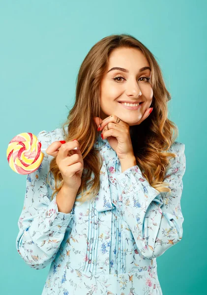 Junge hübsche Smiley-Frau hält Lutscher in den Händen über blauem Ba — Stockfoto