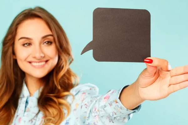 Young woman holding empty thought bubble over blue background — Stock Photo, Image