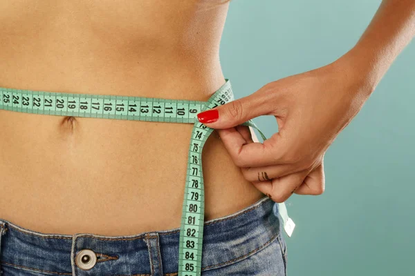 Woman measuring her waist over blue background. Wellness concept — Stock Photo, Image