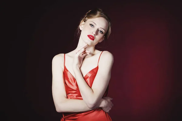 Mladá krásná blonďatá žena v červených šatech na červeném pozadí. FA — Stock fotografie