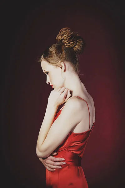 Jonge mooie blonde vrouw in rode jurk op rode achtergrond. FA — Stockfoto