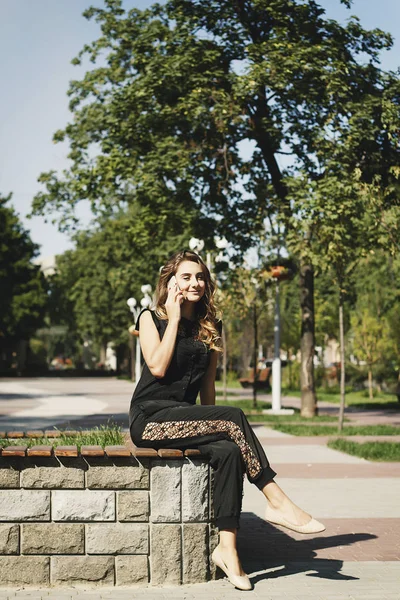Genç güzel kadın parkta oturmuş telefonda söz — Stok fotoğraf