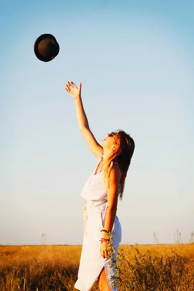 Молодая красивая счастливая девушка бросает шляпу в воздух — стоковое фото