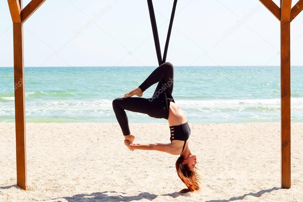 young beautiful brunette woman doing fly yoga. Sitting in hammoc