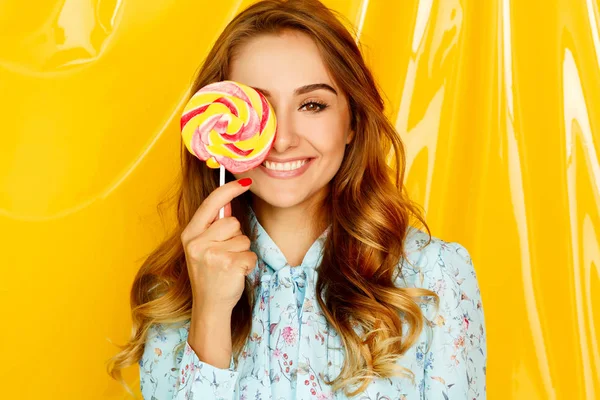 Porträt einer glücklichen hübschen Studentin, die süße Bonbons über sich hält — Stockfoto