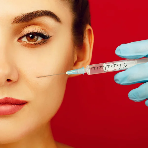 Half face beauty woman portrait with syringe on her skin over re — Stock Photo, Image