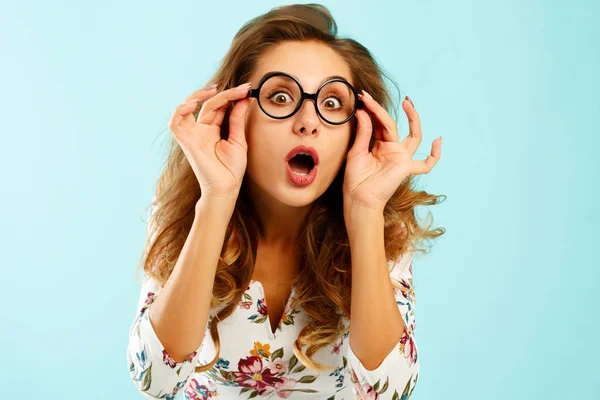 Divertido bonita joven sosteniendo gafas redondas sobre fondo azul —  Fotos de Stock