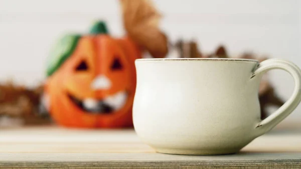 Picture of blurred pumpkie over wooden background with cup of te — Stock Photo, Image