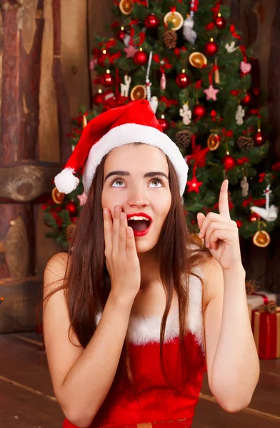 Joven mujer feliz en rojo sombrero de santa y vestido rojo sentado cerca ne — Foto de Stock