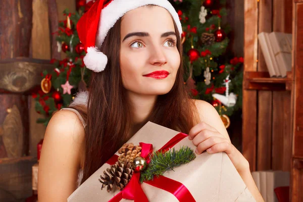 Gelukkig jongedame in rode kerstmuts en rode jurk zitten in de buurt van ne — Stockfoto