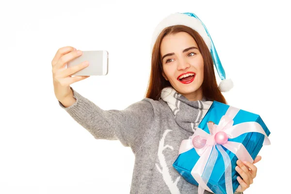 Giovane donna felice in maglione caldo prendendo il suo selfie su bianco — Foto Stock