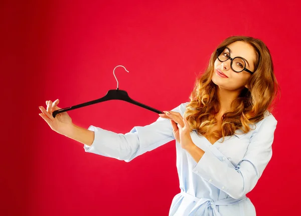 Joven mujer feliz sosteniendo percha vacía sobre fondo rojo —  Fotos de Stock