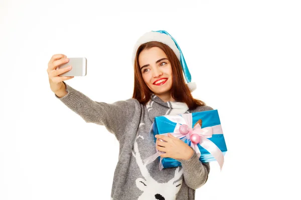 Giovane donna felice in maglione caldo prendendo il suo selfie su bianco — Foto Stock