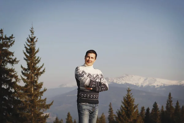 Joven hombre feliz de pie en la cima de la montaña en invierno nevado — Foto de Stock