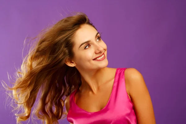 Schöne junge Frau posiert im Studio vor violettem Hintergrund. f — Stockfoto