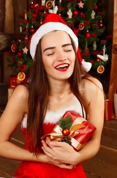 Gelukkig jongedame in rode kerstmuts en rode jurk in de buurt van Nieuwjaar t — Stockfoto