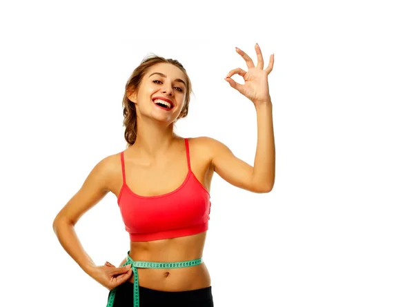 Woman measuring her waist and showing hand ok sign over white ba — Stock Photo, Image